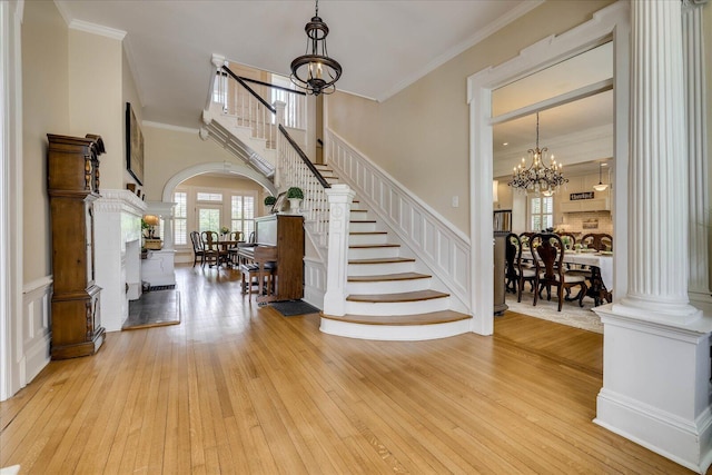 entrance foyer featuring arched walkways, a notable chandelier, crown molding, stairway, and hardwood / wood-style floors