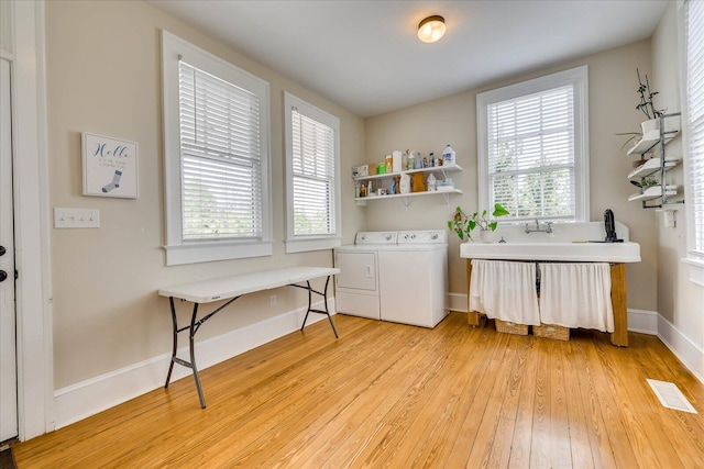 washroom featuring laundry area, separate washer and dryer, light wood finished floors, and plenty of natural light