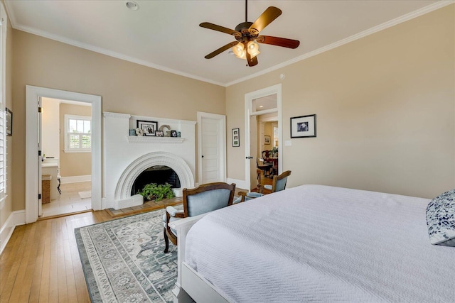 bedroom featuring baseboards, a brick fireplace, a ceiling fan, crown molding, and light wood finished floors