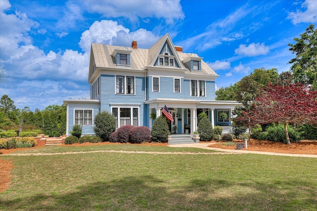 view of front of property with a front yard, a chimney, and covered porch