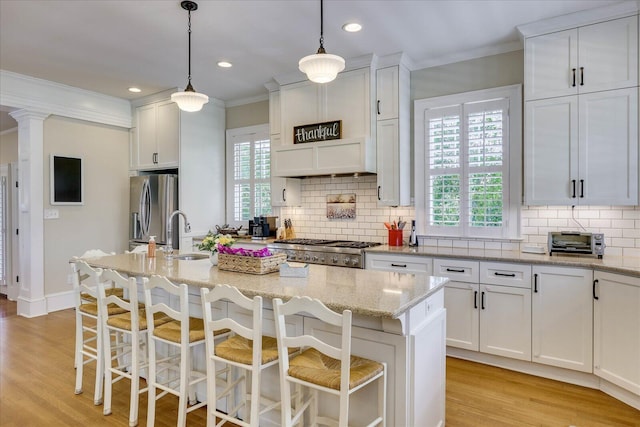 kitchen with white cabinets, stainless steel fridge, a sink, crown molding, and stove