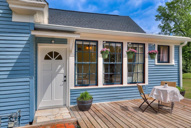 exterior space featuring a wooden deck and a shingled roof