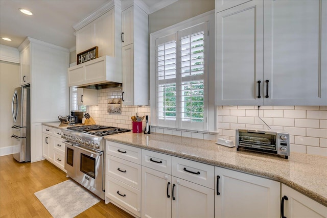 kitchen with light wood-style floors, white cabinets, recessed lighting, appliances with stainless steel finishes, and a toaster