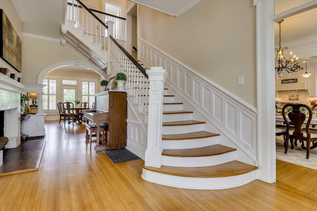 stairs featuring ornamental molding, a high ceiling, hardwood / wood-style floors, and a fireplace