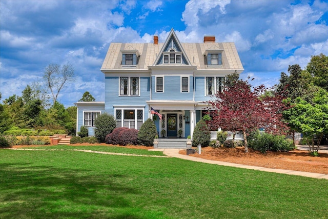 view of front of property with a front lawn, mansard roof, and a chimney