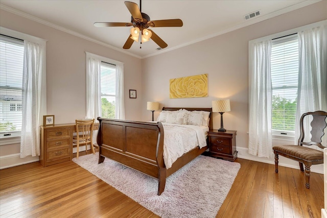 bedroom with visible vents, baseboards, a ceiling fan, crown molding, and light wood-style flooring