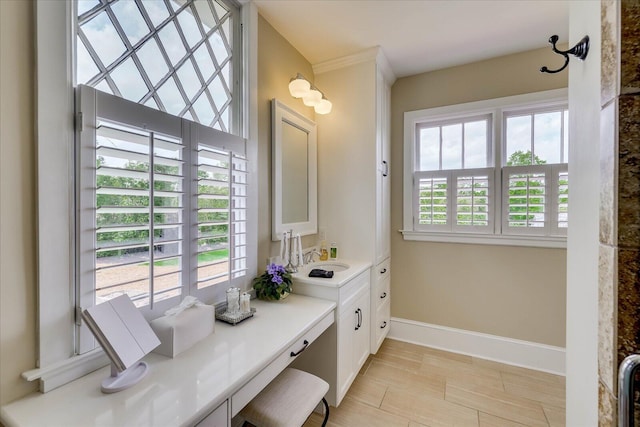 bathroom with vanity, baseboards, and a healthy amount of sunlight