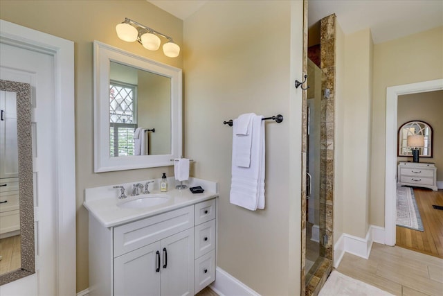 full bathroom featuring a shower stall, wood finished floors, vanity, and baseboards