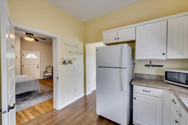 kitchen featuring freestanding refrigerator, ceiling fan, dark wood finished floors, white cabinets, and stainless steel microwave