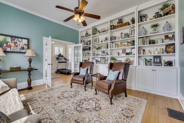 living area with light wood-style floors, visible vents, crown molding, and a ceiling fan
