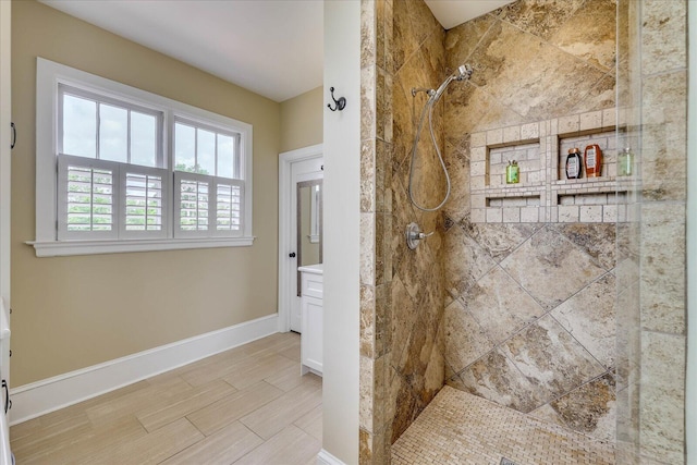 full bath with a tile shower and baseboards
