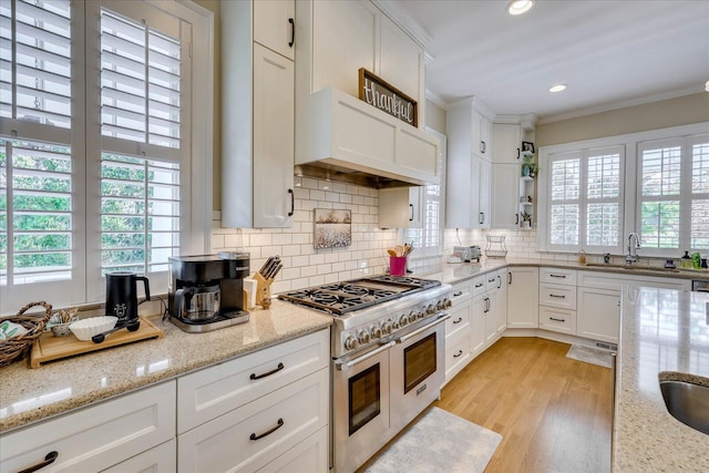 kitchen featuring crown molding, light stone countertops, white cabinets, decorative backsplash, and range with two ovens