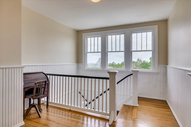 interior space featuring wood-type flooring, wainscoting, and a healthy amount of sunlight