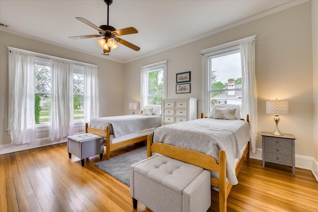 bedroom with baseboards, ornamental molding, light wood-style flooring, visible vents, and ceiling fan