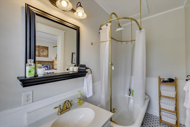 ensuite bathroom featuring a shower with shower curtain, vanity, ensuite bath, crown molding, and a wainscoted wall
