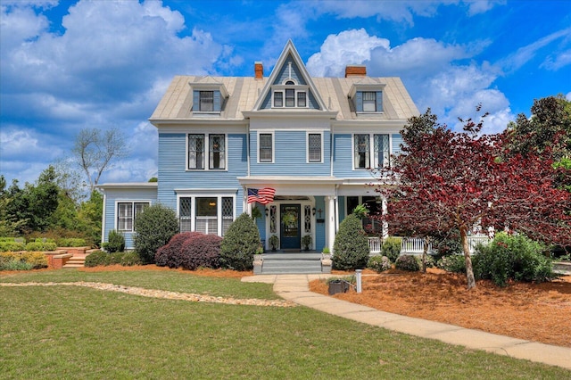 victorian-style house with a porch, a front lawn, mansard roof, and a chimney