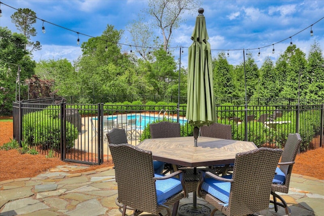 view of patio with outdoor dining space, fence, and a fenced in pool