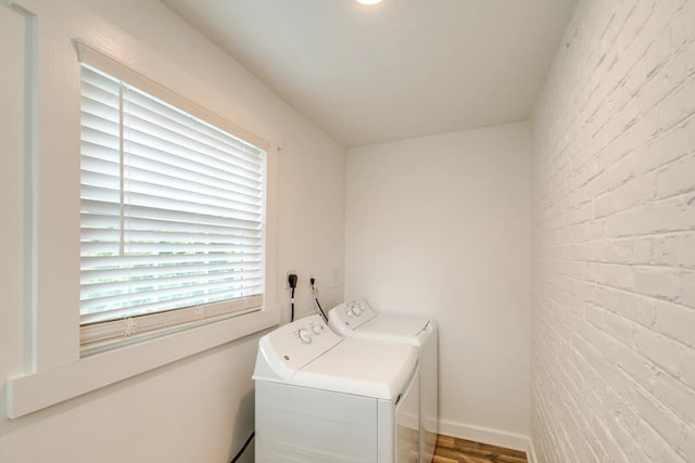 clothes washing area with washing machine and dryer and brick wall