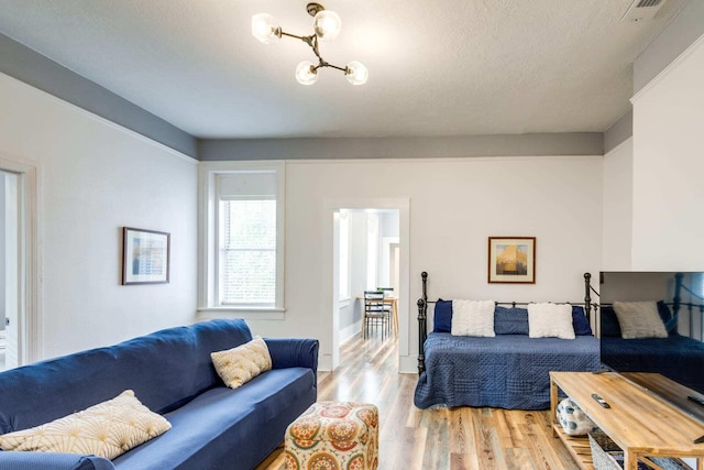 living room featuring a chandelier, light hardwood / wood-style flooring, and a textured ceiling