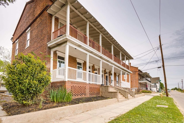 view of side of property featuring a balcony and covered porch