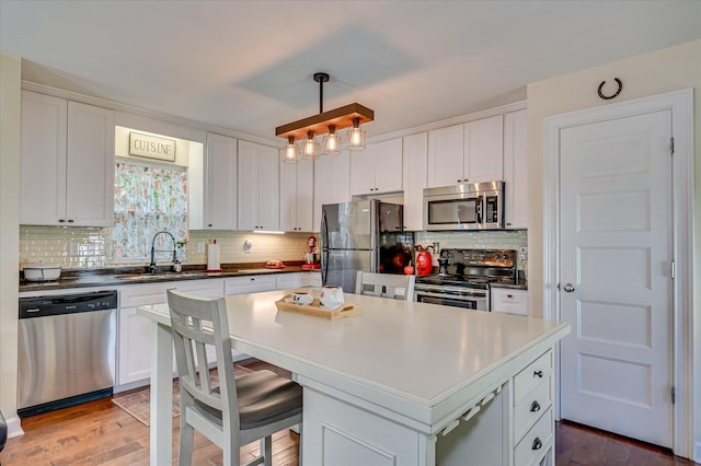 2010 Battle, Augusta, GA 30904 - kitchen featuring appliances with stainless steel finishes, white cabinets, tasteful backsplash, a kitchen island, and light wood-style floors