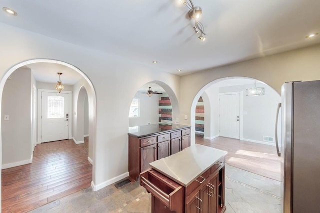 kitchen with a wealth of natural light, stainless steel fridge, and decorative light fixtures