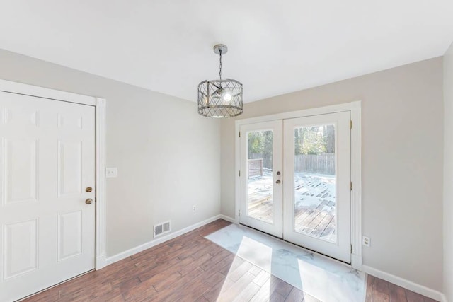 entryway featuring dark hardwood / wood-style flooring, a notable chandelier, and french doors