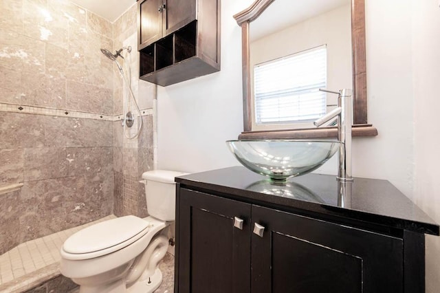 bathroom featuring tiled shower, vanity, and toilet