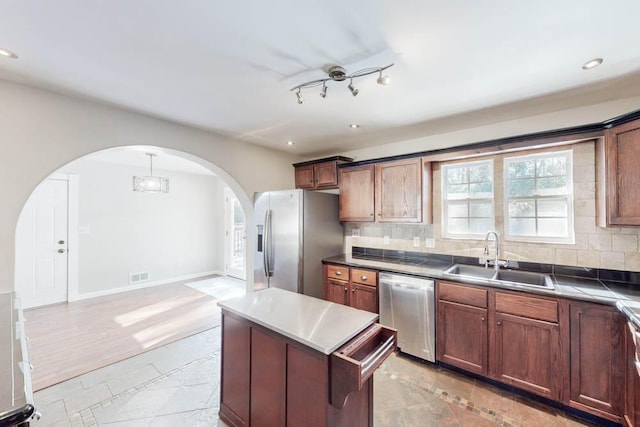 kitchen featuring tasteful backsplash, sink, stainless steel appliances, and a center island