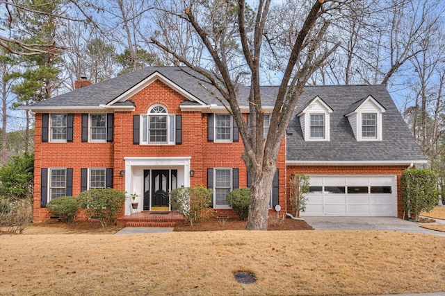 colonial home featuring a garage and a front lawn