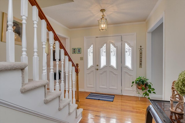 foyer featuring hardwood / wood-style flooring, ornamental molding, and a textured ceiling