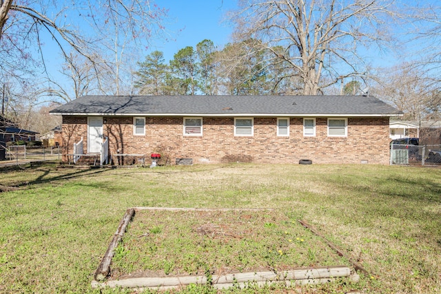 rear view of house with crawl space, brick siding, a yard, and fence