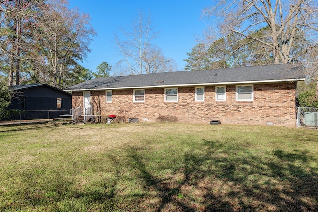 rear view of property featuring crawl space, brick siding, and a lawn