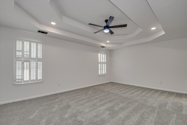 unfurnished room with a raised ceiling, recessed lighting, a ceiling fan, carpet floors, and baseboards
