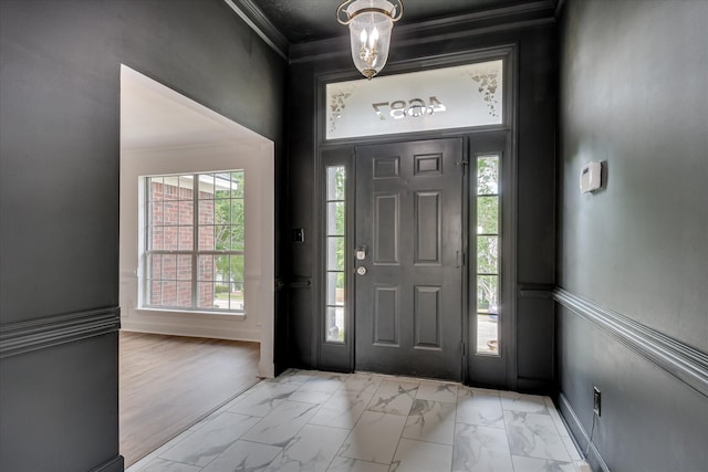 foyer entrance with light marble finish floors, crown molding, and baseboards