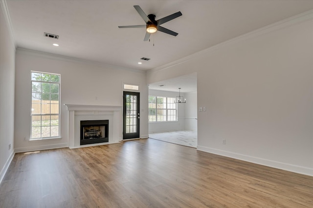 unfurnished living room featuring crown molding, healthy amount of natural light, a fireplace with flush hearth, ceiling fan, and baseboards