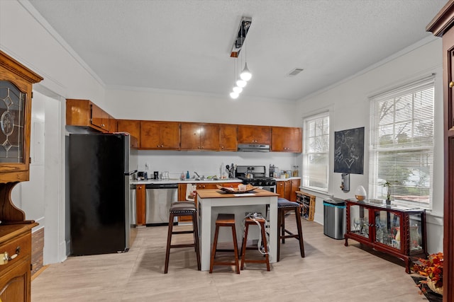 kitchen featuring appliances with stainless steel finishes, a breakfast bar, pendant lighting, ornamental molding, and a textured ceiling