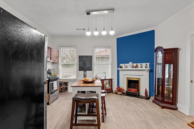 kitchen featuring a breakfast bar, appliances with stainless steel finishes, light hardwood / wood-style floors, a textured ceiling, and decorative light fixtures