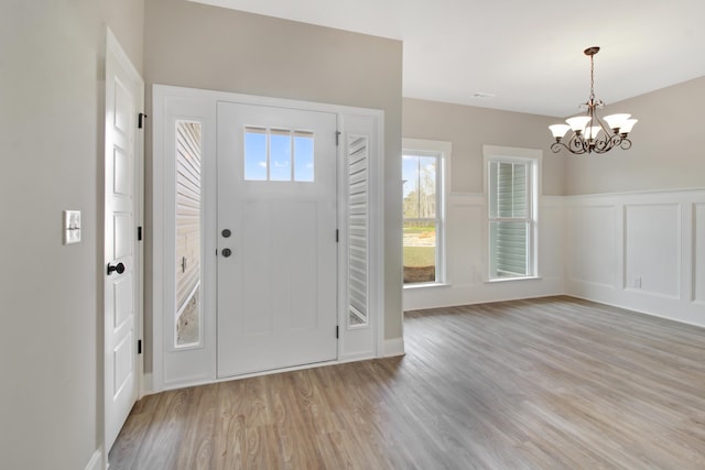 entryway with a wealth of natural light, light hardwood / wood-style floors, and a chandelier