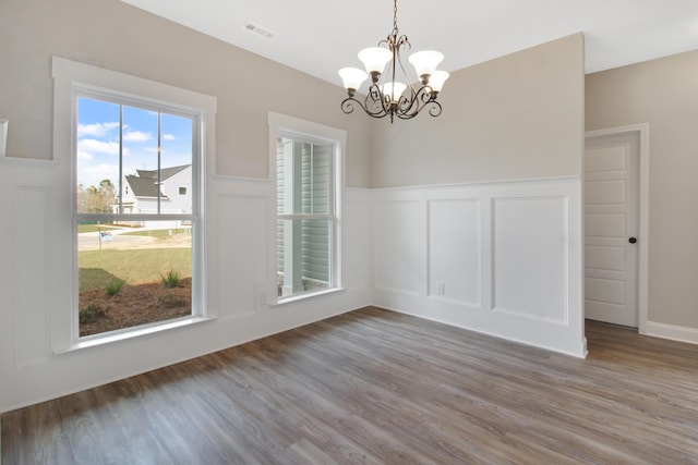 unfurnished dining area featuring wood-type flooring and a notable chandelier