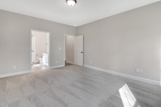 unfurnished bedroom featuring connected bathroom and light colored carpet