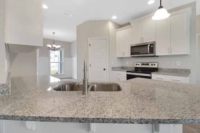 kitchen with white cabinetry, stainless steel appliances, sink, and hanging light fixtures