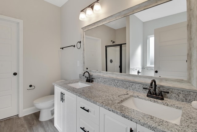 bathroom with vanity, wood-type flooring, a shower with door, and toilet