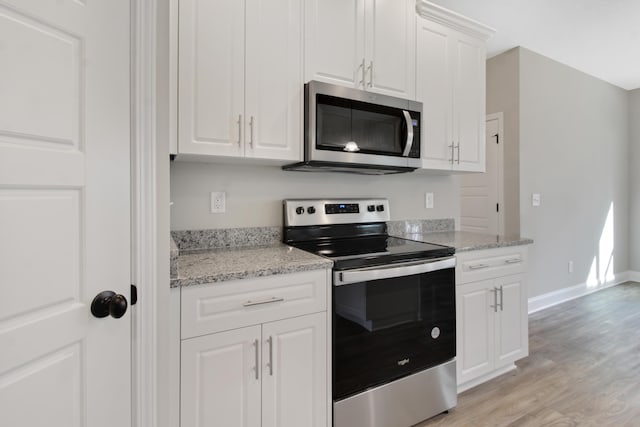 kitchen featuring stainless steel appliances, white cabinetry, light stone countertops, and light wood-type flooring