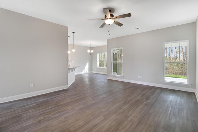 unfurnished living room featuring dark hardwood / wood-style flooring and ceiling fan with notable chandelier