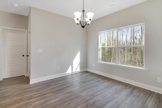 unfurnished room featuring hardwood / wood-style flooring, a wealth of natural light, and a chandelier