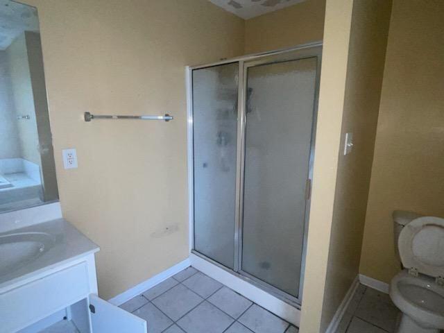 bathroom featuring tile patterned floors, vanity, toilet, and an enclosed shower