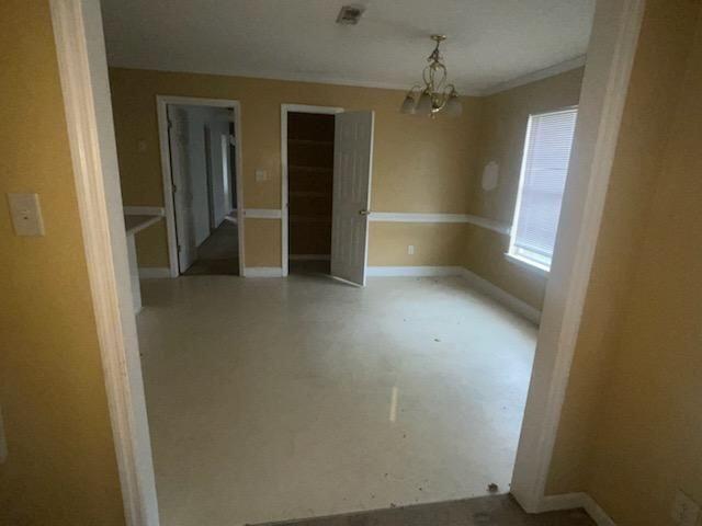 unfurnished room featuring a chandelier