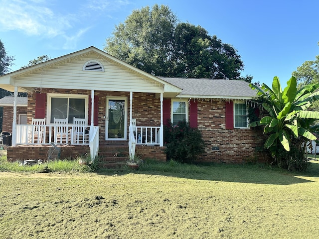 ranch-style house featuring covered porch and a front yard