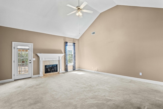 unfurnished living room with visible vents, a tiled fireplace, carpet flooring, high vaulted ceiling, and a ceiling fan